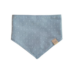 May include: A light blue bandana with a white cross pattern and a small brown label with the text "Puddles" on it.