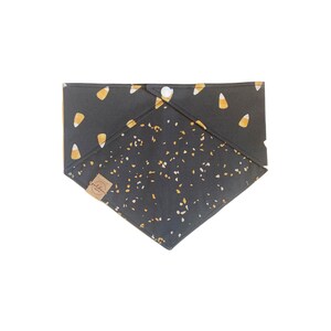 Puede incluir: Bandana para perro negra y dorada con un patr&oacute;n de ma&iacute;z dulce. La bandana tiene un cierre de bot&oacute;n.