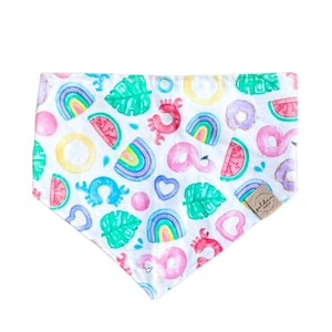 May include: White bandana with a colorful summer-themed print. The print features rainbows, watermelon slices, donuts, flamingos, palm leaves, hearts, and crabs. The bandana has a small brown tag with the word "Little" on it.