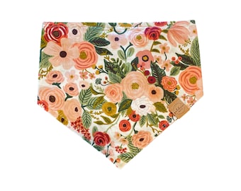 May include: A white bandana with a floral print featuring pink, red, and green flowers. The bandana has a brown leather label with the text "Golden" on it.