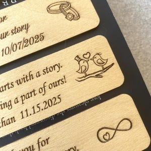 May include: Four wooden plaques with engraved designs and text. The top plaque has two interlocking rings and the text "our story 10/07/2025". The second plaque has two birds with a heart and the text "starts with a story. being a part of ours! han 11.15.2025". The third plaque has an infinity symbol with a heart and the text "love pleasures she discovered back then". The bottom plaque has the text "R".