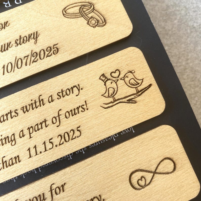 May include: Four wooden plaques with engraved designs and text. The top plaque has two interlocking rings and the text "our story 10/07/2025". The second plaque has two birds with a heart and the text "starts with a story. being a part of ours! han 11.15.2025". The third plaque has an infinity symbol with a heart and the text "love pleasures she discovered back then". The bottom plaque has the text "R".