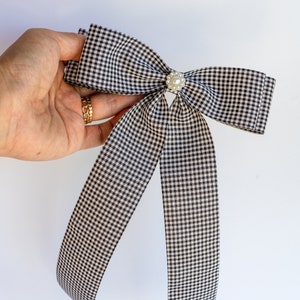 May include: A black and white gingham bow with a pearl button in the center.
