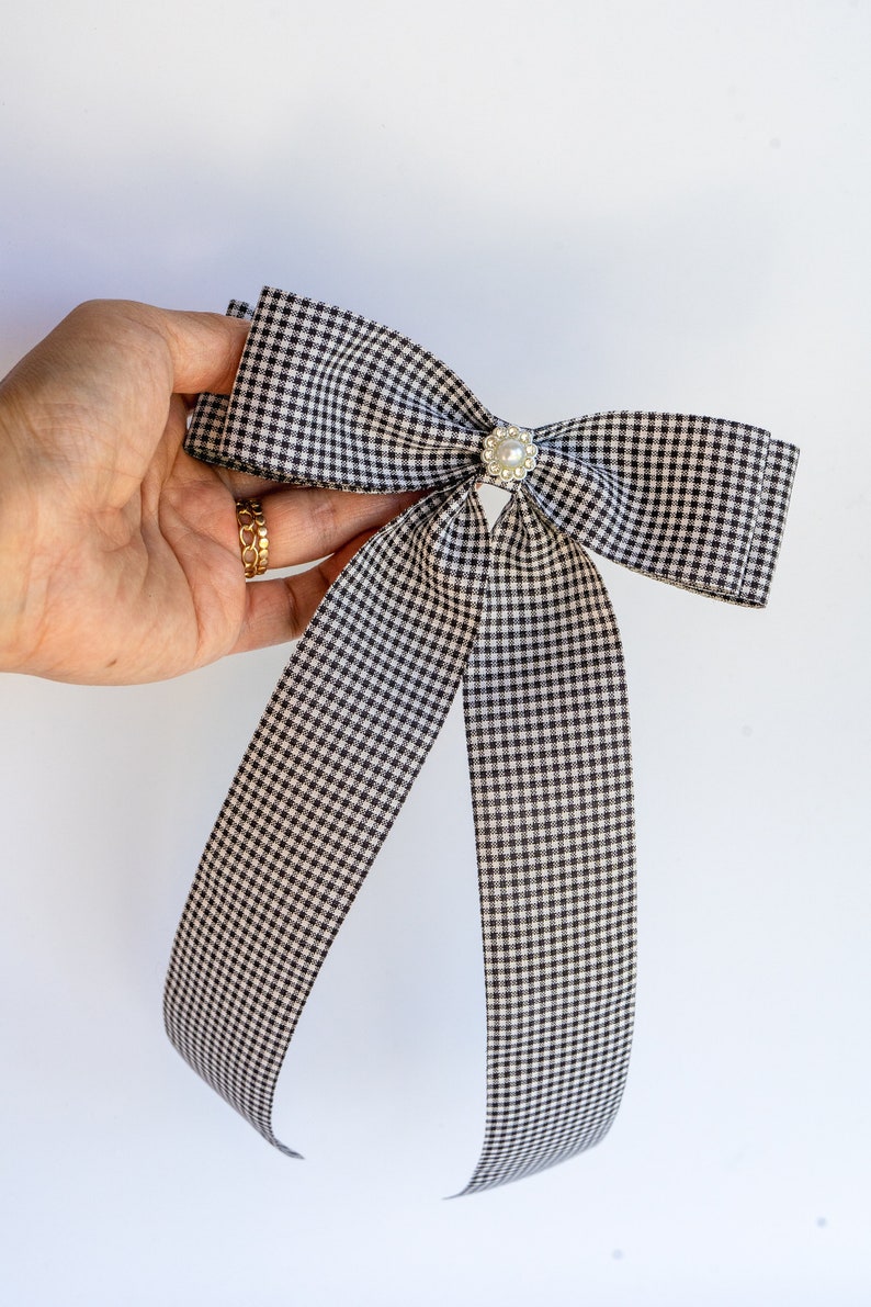 May include: A black and white gingham bow with a pearl button in the center.
