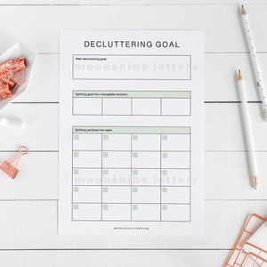 May include: A printable decluttering goal worksheet with sections for listing the main decluttering goal, splitting the goal into manageable sections, and splitting sections into tasks. The worksheet has a green and white color scheme.
