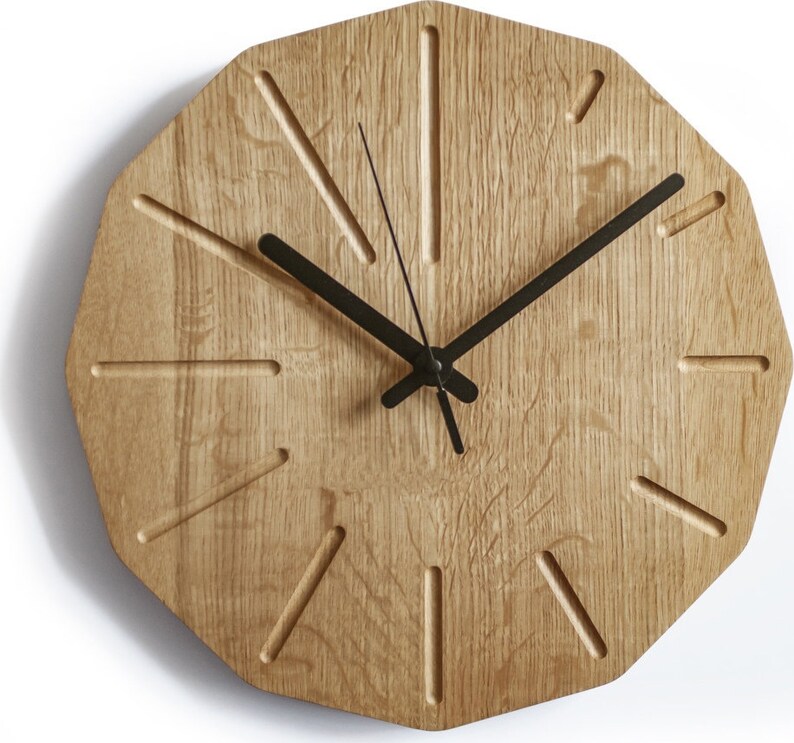 May include: A wooden wall clock with black hands and a unique octagonal shape. The clock face has a light wood grain and features a simple design with black hour markers.