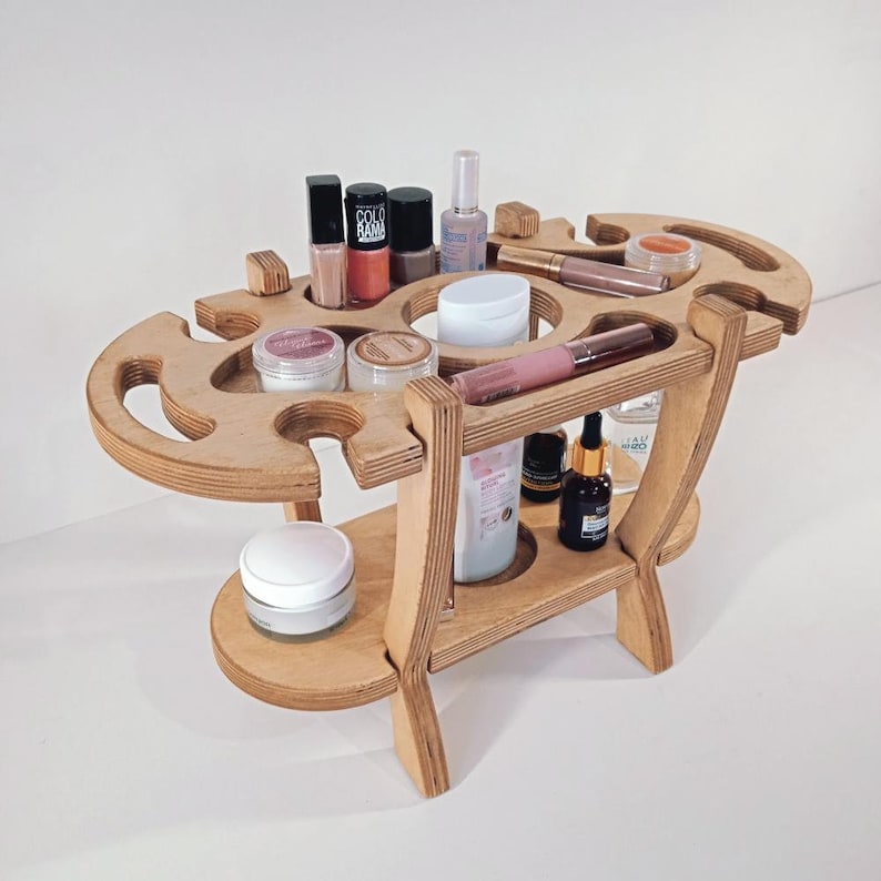 Puede incluir: Un organizador de madera de dos niveles con m&uacute;ltiples compartimentos para guardar cosm&eacute;ticos y productos de belleza. El organizador est&aacute; hecho de madera marr&oacute;n claro y tiene un acabado natural. Cuenta con una variedad de compartimentos para guardar botellas, frascos y tubos de diferentes tama&ntilde;os.