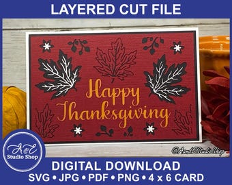Pode incluir: Um cartão vermelho com um design de corte em camadas que apresenta folhas pretas e brancas e o texto "Happy Thanksgiving".