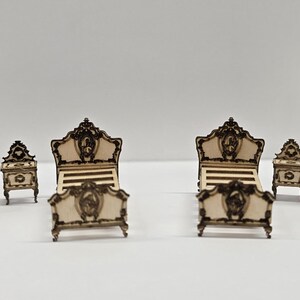 May include: Miniature bedroom furniture set. The set includes a chest of drawers, two bedside tables, two beds, and a wardrobe. The furniture is made of light-coloured wood with dark brown decorative accents. The bed frames have ornate headboards and footboards.