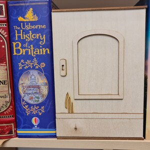 Pu&ograve; includere: Una libreria con una variet&agrave; di libri, tra cui "The Usborne History of Britain", "Jules Verne Seven Novels", "A Beautiful Spy" di Rachel Hore e "The Secret Garden" di Frances Hodgson Burnett. La libreria &egrave; in legno e ha una piccola porta al centro.