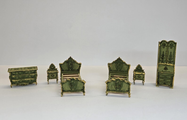 May include: A miniature bedroom suite in a classic style. The set includes a chest of drawers, two bedside tables, two beds, and a wardrobe. The furniture is painted green with gold accents.
