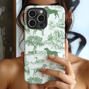 May include: A white iPhone case with a green and white pattern of dogs, ducks, and trees. The case has a camera lens cutout and a raised lip around the edges.