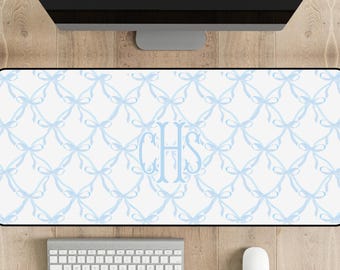 May include: A white desk mat with a blue bow pattern and the monogram "CHS" in the center. The mat is on a wooden surface with a computer monitor, keyboard, and mouse.