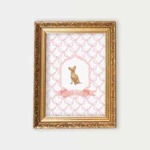 May include: A framed print with a pink and white pattern featuring a small brown chihuahua dog in a pink and white frame. The print has the text "Luna Belle" on a pink ribbon.