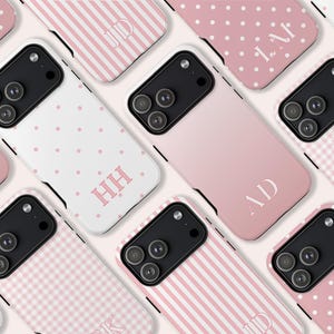 May include: A collection of personalized phone cases in various designs. The cases feature a range of patterns, including polka dots, stripes, and gingham, in shades of pink and white. Each case is adorned with initials in a matching color, creating a cohesive and stylish aesthetic.
