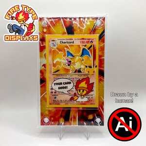 May include: A rectangular acrylic trading card display case featuring a vibrant orange and yellow flame-patterned background. The case holds a Charizard trading card with a speech bubble graphic that reads YOUR CARD HERE and a cartoon character.