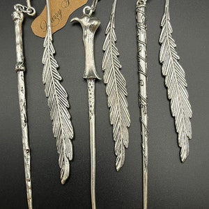 May include: A selection of silver metal bookmarks in various designs. The bookmarks feature wand and feather shapes. A small tag with the text "Harry Potter" is also visible.