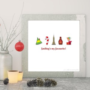 May include: White framed print featuring a red, white and green elf hat, a red and white candy cane, a grey skyscraper, a brown bottle and a red and yellow toy in a box. The text "Smiling's my favourite!" is below the icons.