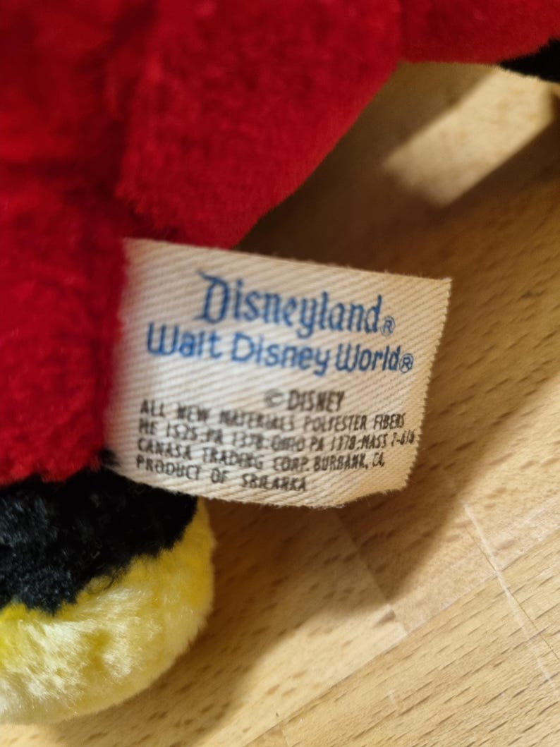 May include: A red and black plush toy with a yellow accent. The toy has a tag that reads "Disneyland Walt Disney World&reg;" and "&copy; Disney All new materials polyester fibers.  Made in China.  SR 1325-PA 1178-MASS 7-419.  Canasa Trading Corp. Burbank, CA.  Product of Sri Lanka."