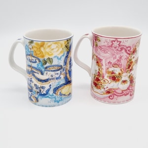 Peut inclure: Deux tasses en céramique avec des motifs floraux. La tasse de gauche a un motif floral bleu et blanc avec une rose jaune. La tasse de droite a un motif floral rose et blanc avec une rose rouge.