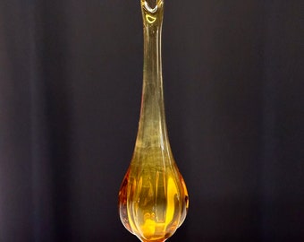 May include: A tall, amber glass vase with a slender neck and a flared base. The vase has a textured, ribbed design.