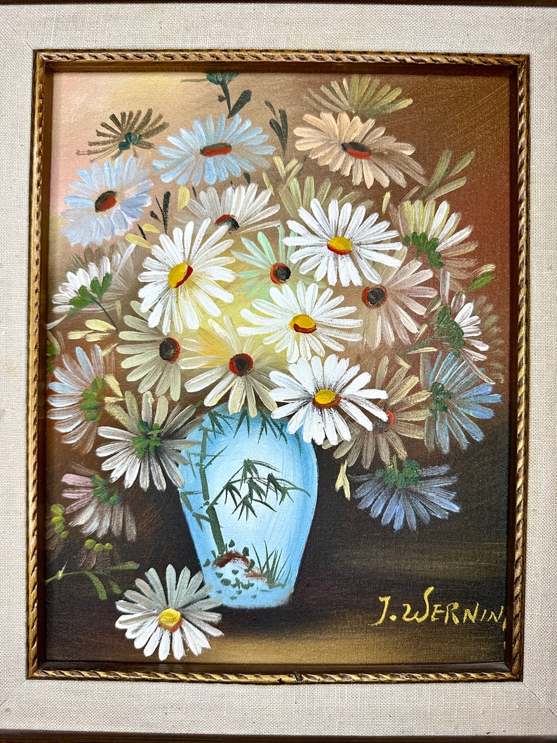 May include: A painting of a bouquet of white daisies in a blue and white vase with a bamboo design. The vase is sitting on a brown surface. The painting is signed "J.Wernin" in the lower right corner.
