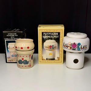 May include: A collection of stoneware potpourri simmer pots with decorative designs. One pot has a swan motif, another features a heart and figures, and the third is in its original box. The boxes read "Potpourri Simmer Pot" and "Stoneware Potpourri Pot".