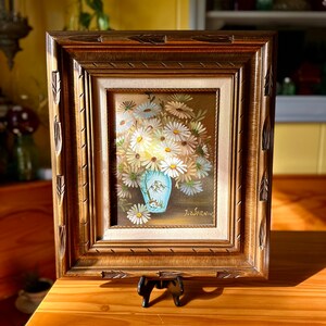 May include: A framed painting of a bouquet of white daisies in a blue vase. The painting is signed "J. Zwernin" in the lower right corner.