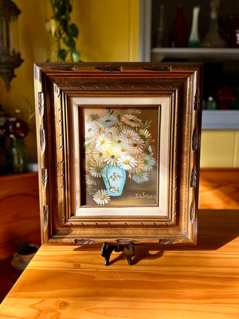 May include: A framed painting of a bouquet of white daisies in a blue vase. The painting is signed "J. Zwernin" in the lower right corner.