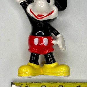 K&ouml;nnte beinhalten: Eine Keramikfigur von Micky Maus. Die Figur ist schwarz, wei&szlig;, rot und gelb. Micky winkt mit der rechten Hand. Die Figur ist etwa 10 cm hoch.