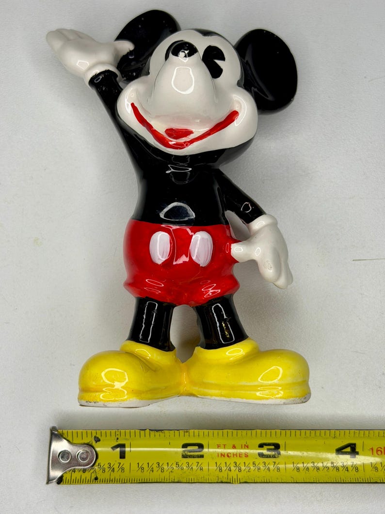 K&ouml;nnte beinhalten: Eine Keramikfigur von Micky Maus. Die Figur ist schwarz, wei&szlig;, rot und gelb. Micky winkt mit der rechten Hand. Die Figur ist etwa 10 cm hoch.