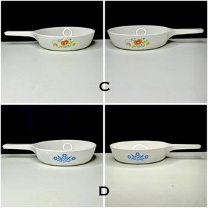 May include: Four white ceramic skillets with different floral designs. Two skillets feature a blue floral design and two skillets feature a multi-colored floral design.