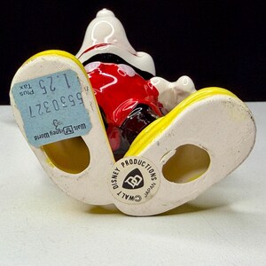 K&ouml;nnte beinhalten: Eine Keramikfigur von Mickey Mouse mit wei&szlig;em Kopf, roter Hose und gelben Schuhen. Die Figur hat ein blaues Preisschild an einem Fu&szlig; und einen "Walt Disney World"-Aufkleber am anderen. Die Figur ist mit "Disney Productions Japan" gekennzeichnet.