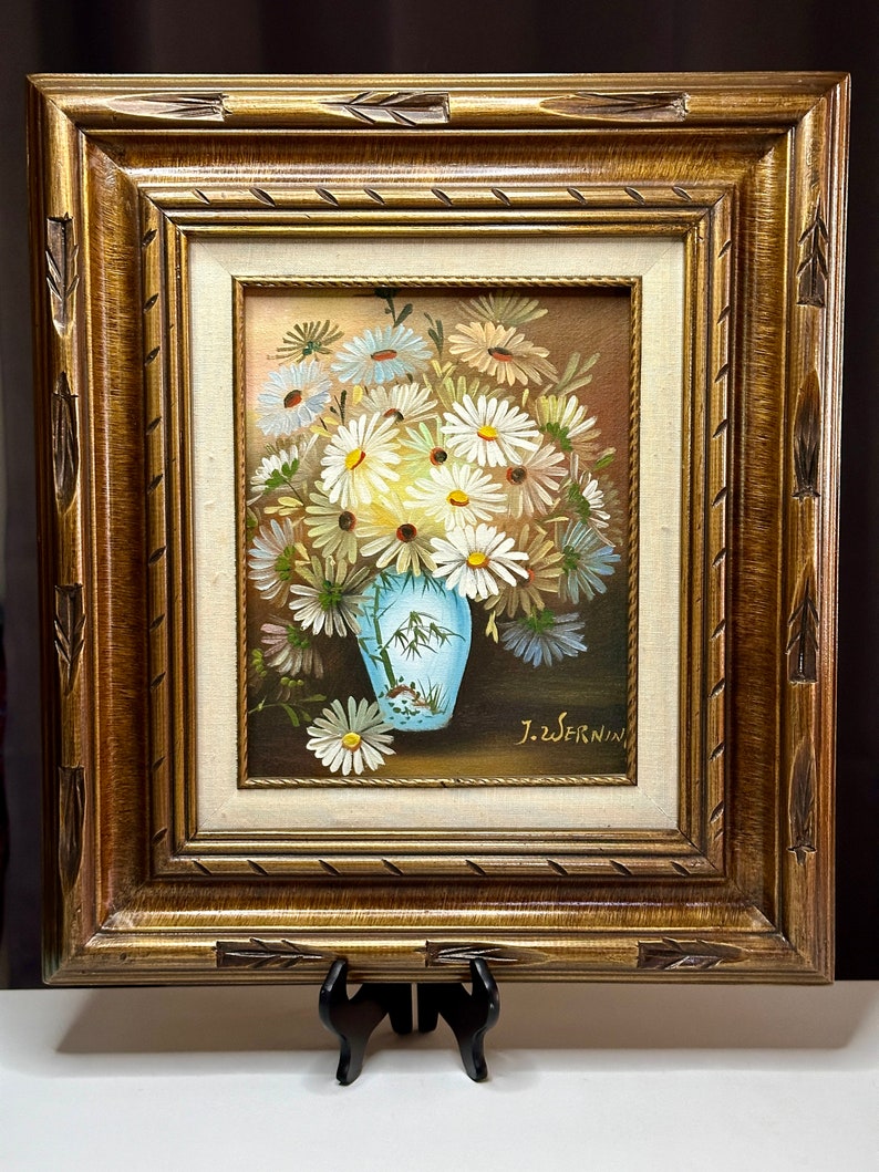 May include: A framed painting of a bouquet of white daisies in a blue and white vase. The painting is signed "J.Z. SERNIN".