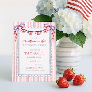 May include: A patriotic birthday party scene featuring a floral arrangement with an American flag, a birthday invitation, and fresh strawberries. The invitation reads "Our All American Girl is Turning Three!" in red and blue. The vase is striped.