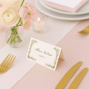 Editable floral place card displayed beside delicate wedding florals and soft candlelight.