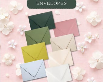 May include: A collection of eight rectangular envelopes in various solid colors including dark green, olive, yellow, light blue, dusty rose, cream, off-white, and white, arranged on a pink background with white flowers and the text ENVELOPES.