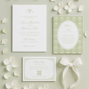 a wedding invitation, a small card, and some white flowers arranged on a light background.