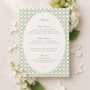 May include: A rectangular menu card featuring a sage green lattice pattern border and a central oval frame. The text lists a three-course meal including salad, filet medallions or butternut squash risotto, and wedding cake, with the initials A|B at the bottom.
