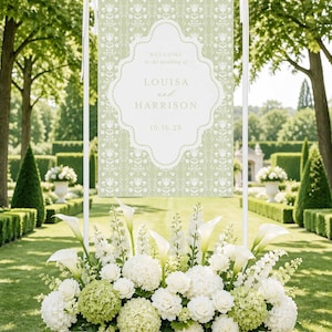 a large white banner with a floral design, surrounded by a beautiful arrangement of white flowers in a white box, set against a backdrop of lush greenery and trees.