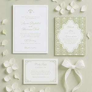 a wedding invitation, a card, and some white flowers arranged on a light background.