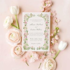 Pink and green watercolor floral wedding invitation suite arranged in a flat lay with blooms and soft pastel accents.”