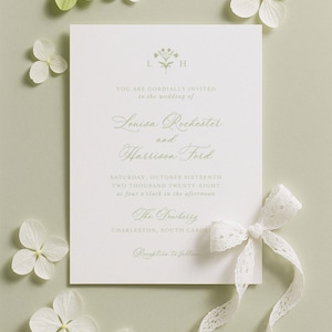 The image is a wedding invitation card with a white background, surrounded by white flowers and a white ribbon.