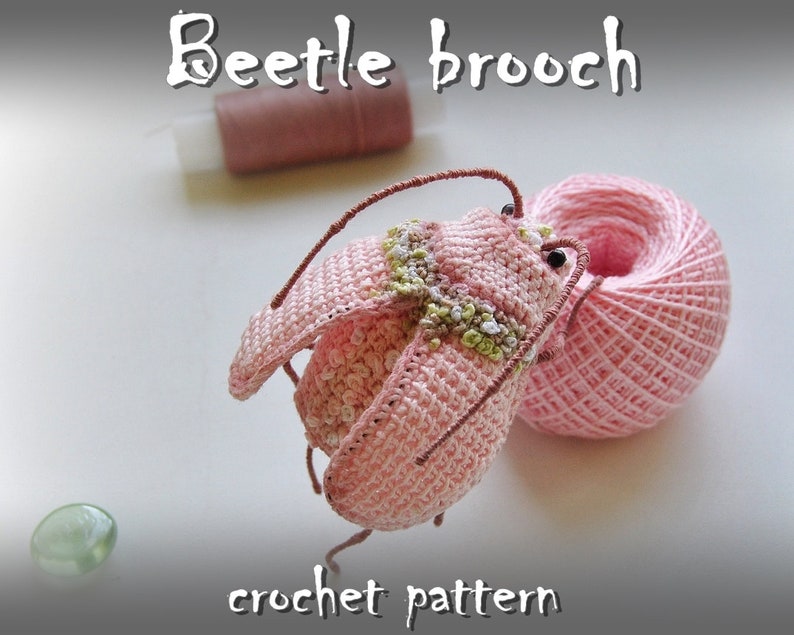 May include: A crochet pattern for a pink beetle brooch. The pattern includes instructions for crocheting the beetle's body, legs, and antennae.