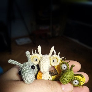 K&ouml;nnte beinhalten: Drei kleine geh&auml;kelte Amigurumi-Spielzeuge. Das erste ist grau mit einer langen Schnauze und gro&szlig;en schwarzen Augen. Das zweite ist wei&szlig; mit einem langen Schnabel und gro&szlig;en gelben Augen. Das dritte ist gr&uuml;n mit einer langen Schnauze und gro&szlig;en wei&szlig;en Augen.