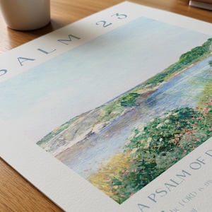 May include: A watercolor print of a river landscape with the text "Psalm 23" and "A Psalm of David". The artwork features a serene river scene with lush greenery and soft blue hues, evoking a sense of peace and tranquility.