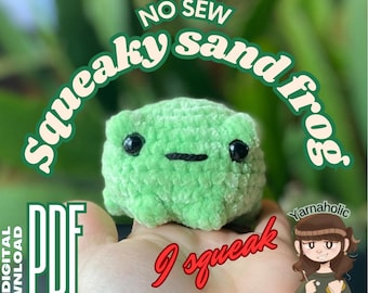 Op de afbeelding: Een groene gehaakte kikker met zwarte ogen en een zwarte mond. De kikker houdt een bord vast met de tekst "Ik piep". De tekst "No Sew Squeaky Sand Frog PDF Digital Download" staat op de achtergrond.