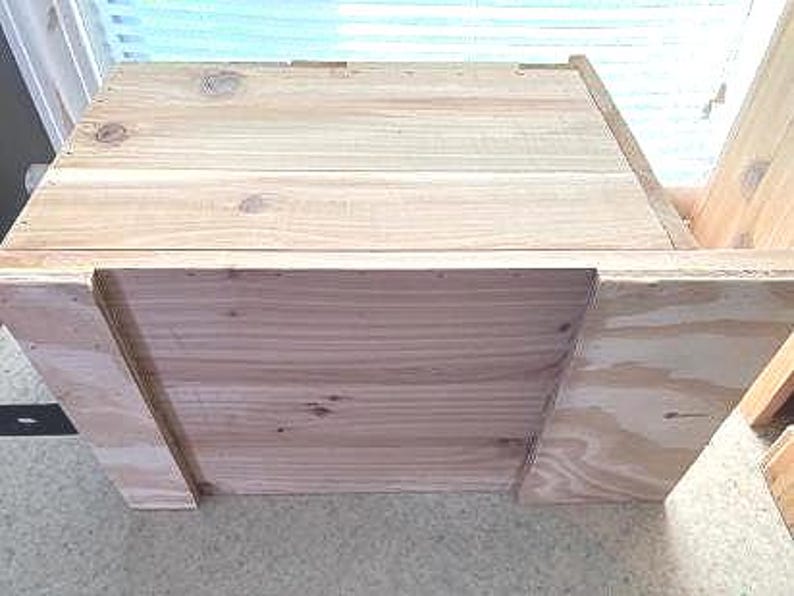 May include: A wooden box with a hinged lid and a plywood back panel. The box is made of unfinished wood and has a natural wood grain.