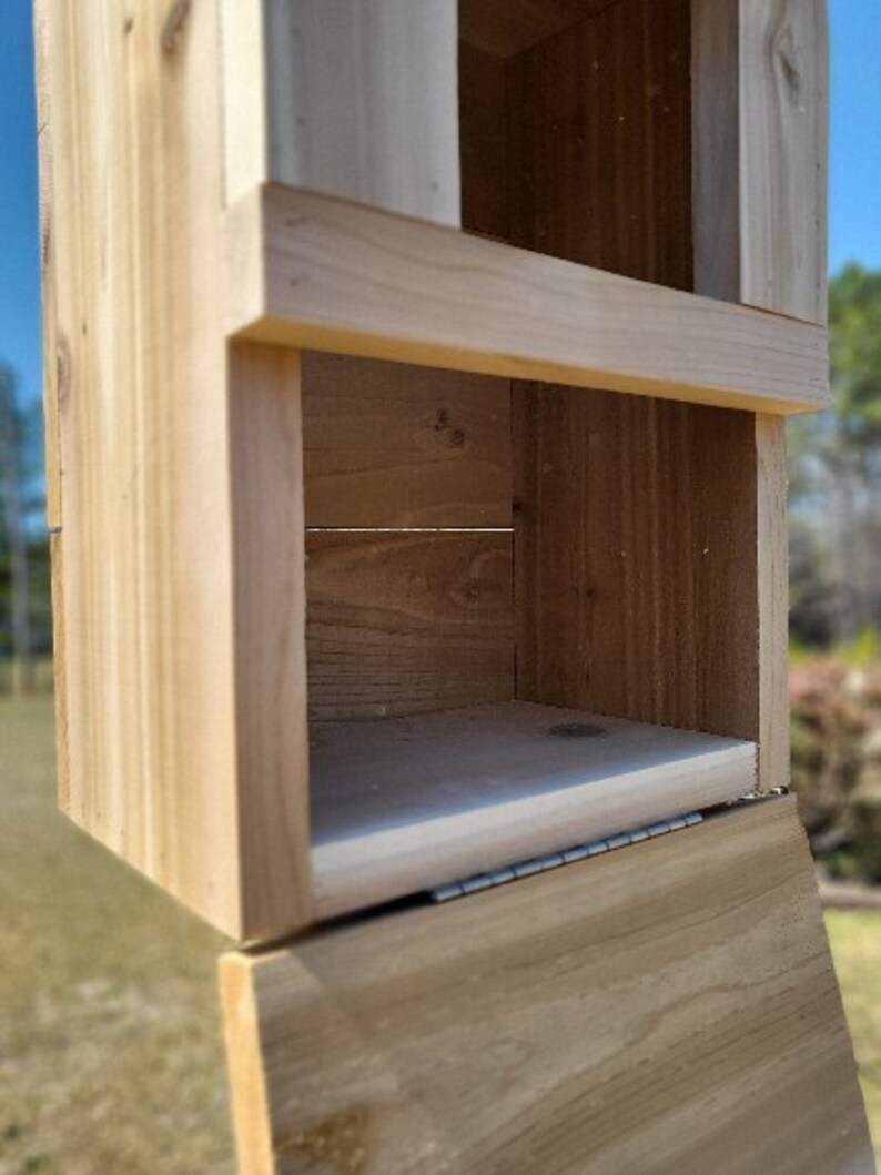 May include: A wooden box with a hinged lid. The box is made of unfinished wood and has a simple design. The box is open and the inside is visible.