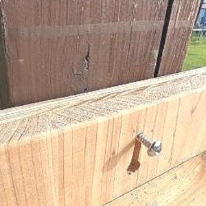May include: Close-up of a wood surface with a silver screw. The screw is partially inserted into the wood.